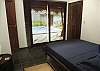 Bedroom 2 (main house) with Queen bed, ensuite bathroom and closet, overlooking the pool through a sliding door with blinds at Casa Gris vacation rental home in Jaco, Costa Rica