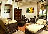 Living room with TV, DVD and stereo, adorned with beautiful Costa Rican modern art paintings, high ceilings with wooden beams and plenty of seating at Hermosa Palms Villa La Costa luxury vacation rental in Playa Hermosa, Costa Rica.