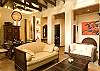 Living room with TV, DVD and stereo, adorned with beautiful Costa Rican modern art paintings, high ceilings with wooden beams and plenty of seating at Hermosa Palms Villa La Costa luxury vacation rental in Playa Hermosa, Costa Rica.