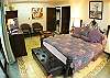 Master Bedroom with wrought iron and wood Queen bed, wooden armoire and chest of drawers, flatscreen TV and DVD and ensuite bathroom at La Flor del Paraiso vacation rental home in Jaco's only beachfront single-family home gated community.