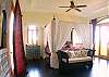 Master bedroom wtih King size four poster bed with canopy, Moroccan textiles and furniture and wooden floor at Casa Exotica vacation rental home in Esterillos, Costa Rica, near Manuel Antonio and Jaco
