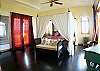 Master bedroom wtih King size four poster bed with canopy, Moroccan textiles and furniture and wooden floor at Casa Exotica vacation rental home in Esterillos, Costa Rica, near Manuel Antonio and Jaco