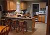 Kitchen with bar stools at counter and is open to the dining area and living room.