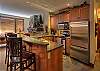 Fully equipped kitchen with stainless steel appliances, granite benchtops, and a heated slate floor.