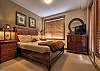 Master bedroom with queen size bed.  the view from the window looks out towards ski run.  A door leads onto balcony with hot tub.
