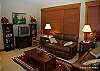 Mid floor lounge area with comfy sofas, TV and views of forest and mountains.