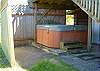 Partially covered hot tub with privacy fence.