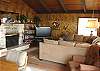 Second view - Living room with a wrap around sectional couch, flat screen TV/DVD, wood burning fireplace and ocean views.