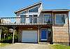 View of house from street. Large upper wrap around deck with table for 4 and a gas BBQ.