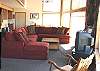 Third view - Lower level - Living room with large sectional, TV/DVD, large picture windows and wood burning fireplace.