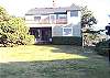 View of house from the ocean side of the house with the large grassy backyard.