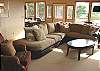 Third view of Upstairs living room with large screen TV/DVD, glass front wood stove and ocean views.