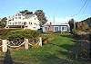 Third view - View of house from street and ocean with large yard.