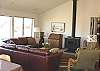 Second view - Middle (entry) level - Living room with large sectional, glass front wood stove and ocean views.