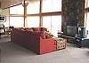 Second view - Lower level - Living room with large sectional, TV/DVD, large picture windows and wood burning fireplace.