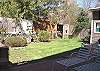Large grassy backyard with deck and hot tub.