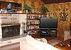 Third view - Living room with a wrap around sectional couch, flat screen TV/DVD, wood burning fireplace and ocean views.