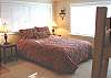 Upper level - Bedroom with a Queen bed and a Twin bunk bed with TV/DVD, ocean views and a door to balcony that over looks the backyard and stream.