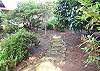 Third view - Large grassy backyard with small bridge that goes across a little stream.