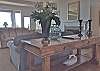 The living room is fresh and inviting with large picture windows offering ocean views