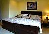 A view of bedroom with comfortable queen size bed table lamp