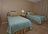 Nicely decorated guest bedroom with two twin beds; bathroom just outside off hallway.