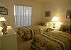 Guest bedroom with twin beds and an adjoining bath with tile shower.