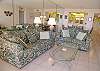Living room with queen sized sofabed, loveseat, mirrored walls & tile floors.