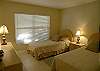Guest bedroom with twin beds and an adjacent bath with tile shower.