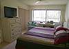 Master bedroom with king size bed, sliding glass doors leading onto the balcony, flatscreen TV, desk with modem, walk-in closet & adjoining bath.