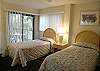Guest bedroom with twin beds, sliding doors to the balcony, bay view and an adjacent bath with tub/shower.