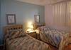 Guest bedroom with twin beds and an adjacent bath with tile shower.