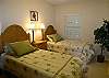 Third bedroom with two twin beds and nearby bath with tile shower.