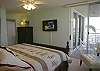 Master bedroom with king size bed, sliding doors onto the balcony, flatscreen TV, walk-in closet and an adjoining bath.