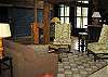 In the center of the living area of the Barn a conversation circles a stacked stone fireplace. Notice the massive doors at the far end of the room.