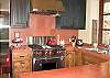 This bright kitchen has rubbed red concrete countertops, and high quality appliances and fixtures.