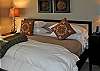 A lower level bedroom with king bed, view of water, and doors opening to deck.