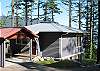 A carport is at the home's entry. A grassy yard is on the water side.