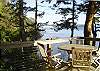 A table for four on this wrap around  deck with views of the coastline and a ferry beyond.