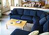 The sunken living room offers a large sofa (sleeper) where one might watch TV or enjoy the views or sun shining in through two walls of windows.