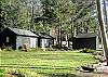 Two sleeping cabins sit at water's edge next to the  lake with a swimmer's dock, float and seperate bath house.