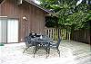 The back deck includes a table and chairs. The doors in the back ground open to a children’s bedroom with three bunk beds.