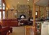 terrific great room with open kitchen, leather seating, and a woodburning fireplace.