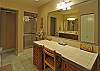The lower level guest bath has a dressing counter and stall shower. Sinks shown in the mirror.