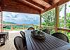 Covered deck with table and seating, overlooking mountain view. 