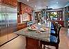 The large gourmet kitchen with a Viking range, a center island, lots of countertop space for several cooks, and a convenient pass-through window to the outdoor poolside dining area. The kitchen area also offers a wet bar with a beverage cooler and ice machine.