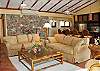 The great room contains plush furniture. Its north wall is crafted from native stone and contains  intricate stone work.   The great room also contains a 34-inch cable TV with VCR, and a Stereo System with both cassette and CD players.