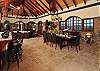 The living area of the Great Room shares space with elegant indoor dining; large custom-made mahogany double doors with screens open out to an arced terrace bordered by bronze railings.