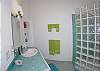 Each lower level bedroom at Luminaria has an in-suite bathroom with glass block shower and shimmering glass tile countertops. The bath connected to  Island Dream also has direct pool deck access.