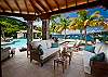 Outside the Main Villa on the Great Cruz Bay side is À La Mer's shaded poolside terrace, furnished with plush upholstered seating for watching the kids in the pool, reading or napping, and a large round table under a roofed pergola for alfresco meals. The pass-through from the kitchen is incorporated into an adjoining counter lined with bar stools.